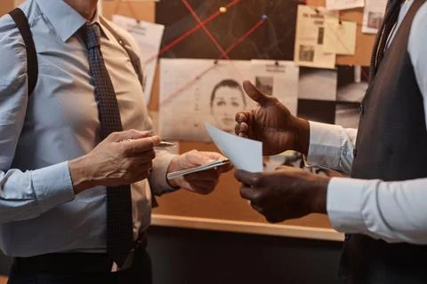 Close up of two unrecognizable detectives discussing case during investigation Stockfoto's