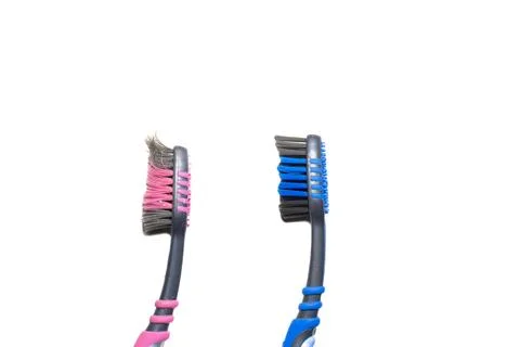 Close-up of two used toothbrushes with pink and blue bristles, set against .. Stock Photos