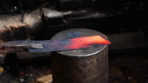 Close up of two vietnamese people pounding piece of hot metal to flatten it Stock Footage 147370294