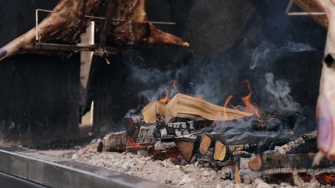 Close up of two whole pigs skewered and grilled in open fire 스톡 동영상 105779253