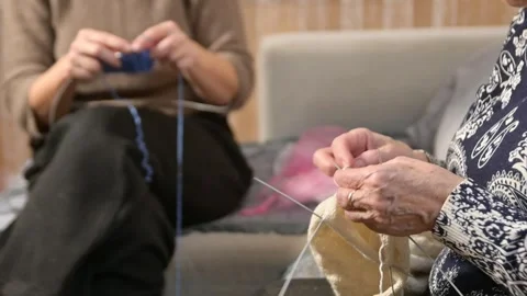 Close-up of two women's hands knitting cozy handmade items with yarn and needles 스톡 동영상 316216050