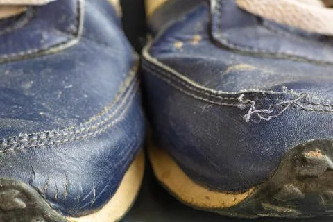 Close-up of two worn-out sneaker toes showing cracked synthetic leather 스톡 사진