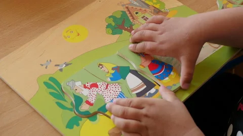 Close up of two years old child collects a fairytale picture from puzzles Stock Footage 63200399
