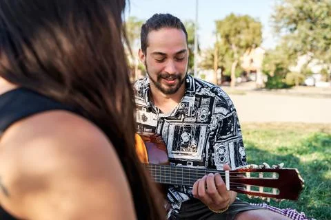 Close up of two young and future parents in a park on a blanket and him playi Stock Photos