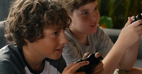 Close up of two young boys age 11 - 13 playing video games with hand controllers Video stock 85373695