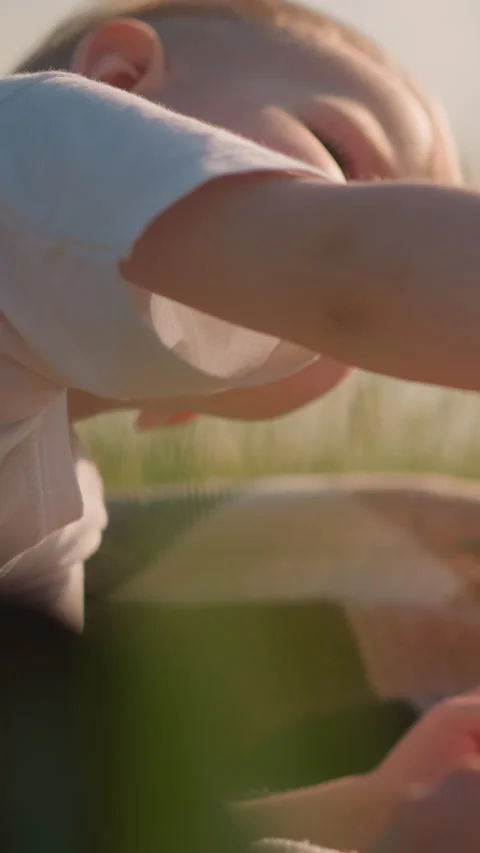 Close-Up of Two Young Boys Sharing Bread in a Grassy Field Stock Footage 308227763