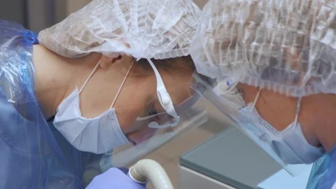 Close-Up Of Two Young Female Doctors In Face Protection Performing Surgery Stock Footage 138064212
