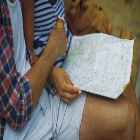Close up of two young people sitting in a bench with a map and ice cream in Stock Footage 69297982