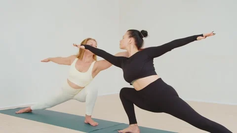 Close-up of two young women practicing partner yoga and stretching on a mat Stockbeeldmateriaal 214931272