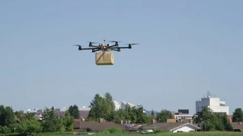 CLOSE UP: UAV drone logistics delivering big brown post package into urban city Stock Footage 81138391