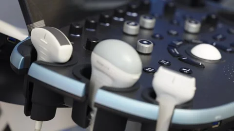 Close up of ultrasound machine control panel with multiple probes resting in Stock Footage 346978239
