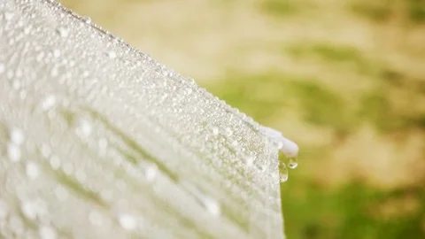 Close-up on umbrella with raining in sunbeam Stockbeeldmateriaal 76328776