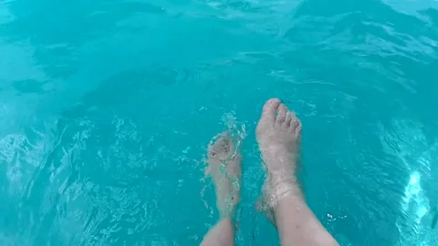Close up un woman's legs moving in blue aquamarine water in a pool. Stock Footage 242091544