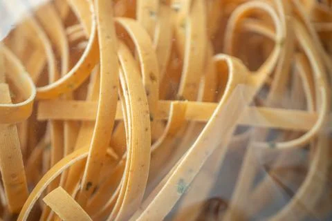 Close-up of uncooked ribbon pasta inside clear plastic. Stock Photos