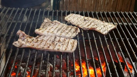 Close up of unidentifiable man flame grilling pork meat on coal fire bbq Stock Footage 104013433