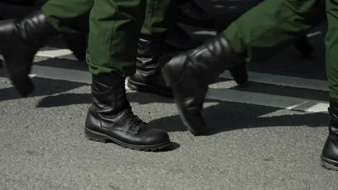 Close-up of uniformed boots marching in sync on asphalt with double white road Stock-Footage 336009325