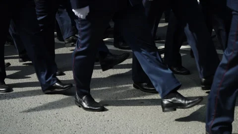 Close-up of uniformed marchers moving in precise formation along an asphalt Stock-Footage 336009452