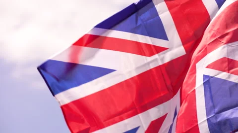 Close up of Union Jack fluttering excitedly against bright cloudy sky Video stock 240488675