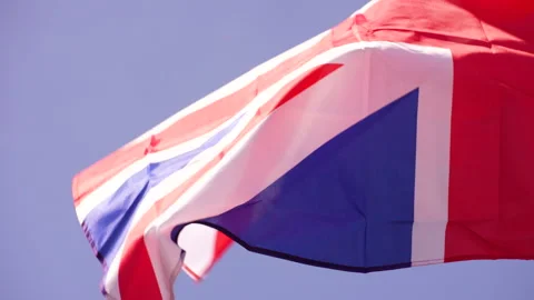 Close up of Union Jack flying vigorously against clear sky Video stock 240437014
