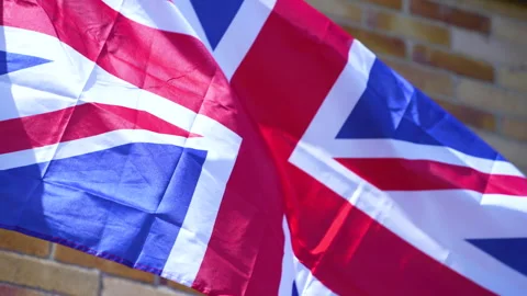 Close up of Union Jack waving and rippling in the breeze against a brick wall Video stock 240518940