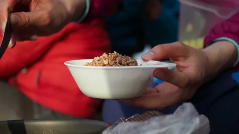 Close up. Unknown female hands pour buckwheat porridge into plastic reusable Stock Footage 152658536