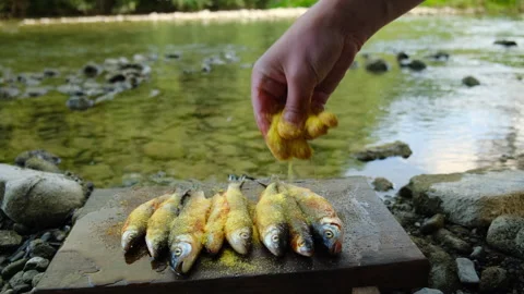 Close up of unknown man adds cornmeal to fish on wooden cutting board Stock Footage 333760991