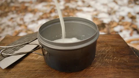 Close up of unknown man pouring milk into pot in winter forest Stock Footage 308720038