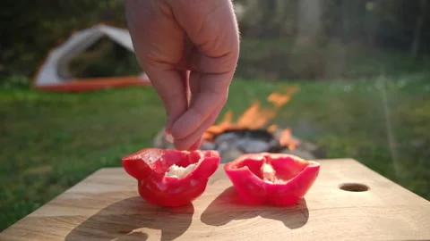 Close up of unknown man stuffed red peppers with cheese near campfire Video stock 271629506