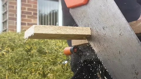 A close up of a unknown person hand sawing a wooden plank outside. DIY, home 動画素材 150313604