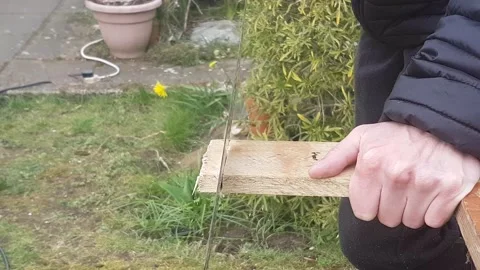 A close up of a unknown person hand sawing a wooden plank outside. DIY, home 動画素材 150313628