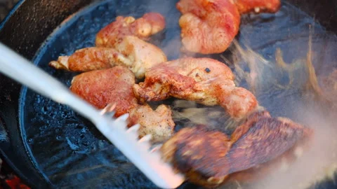 Close up of unknown young man cooking chicken fillet in frying pan at nature Stock Footage 309028765