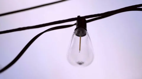 Close Up of Unlit Decorative Light Bulb Suspended From Outdoor String Lighting Stock Footage 337943385