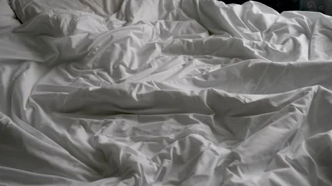 Close-up of unmade bed with white bedsheet and soft blanket in bedroom 스톡 동영상 267005572