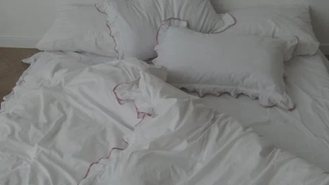 Close-up of unmade bed with white bedsheet and soft blanket in bedroom. Stock Footage 310931138
