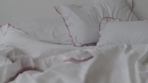 Close-up of unmade bed with white bedsheet and soft blanket in bedroom. 스톡 동영상 311447618