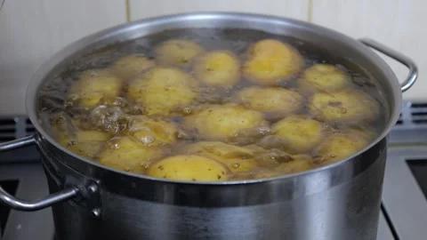 Close-up of unpeeled potatoes boiling in water in a pot in a restaurant kitchen. Stock Footage 321815249