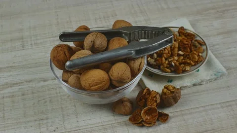 Close-up of unpeeled walnuts lie in a transparent glass bowl, peeled walnut Stock Footage 224013237