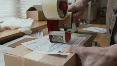 Close-up of Unrecognisable Man Attaching Label to Box with Tape Dispenser Video stock 306283977