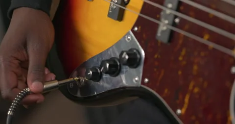 Close up of unrecognizable African man plugging jack cable into guitar and 動画素材 155102081