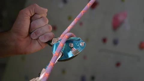 CLOSE UP: Unrecognizable belayer helps a climber descend after climbing a wall Video stock 135190008