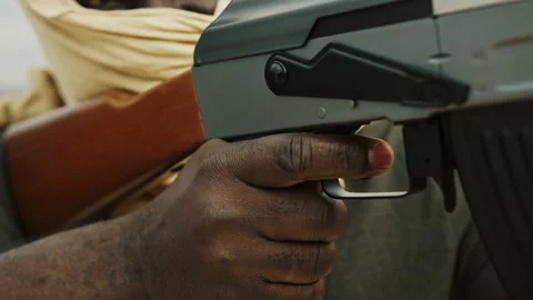 Close up, unrecognizable black man with head covering pulling triger of Video stock 142144127