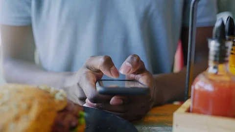 Close up unrecognizable black man texting on smartphone at lunch time in Stock Footage 74711704