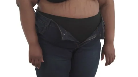 Close-up of unrecognizable black plus size woman's body cannot fasten jeans on Stock Footage 134596337