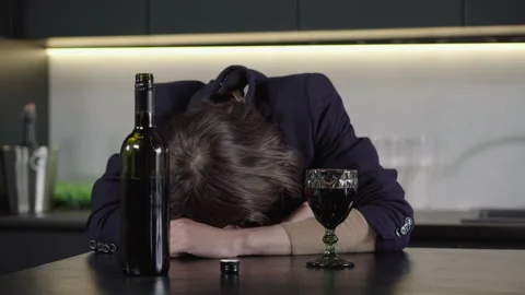 Close-up of unrecognizable brunette man sleeping at the table with wine bottle Video stock 134209187