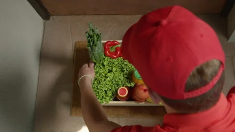 CLOSE UP: Unrecognizable delivery man leaves a box of groceries at doorstep. Stock Footage 138633353