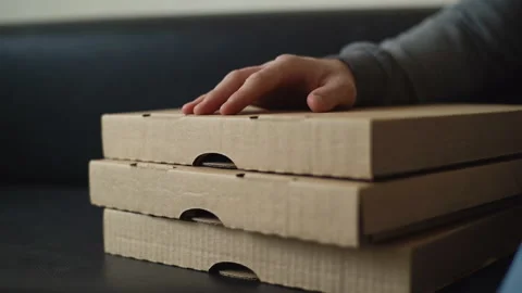 Close-up of unrecognizable delivery man tapping on cardboard pizza box while Video stock 146593972