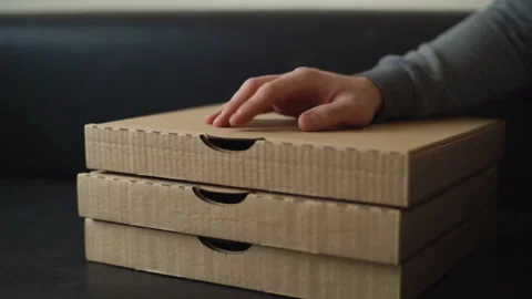 Close-up of unrecognizable delivery man tapping on cardboard pizza box while Stock-Footage 146594050