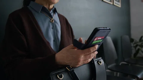 Close-up of Unrecognizable Elderly Woman Using her Smartphone in Bank Office Stock Footage 310115966
