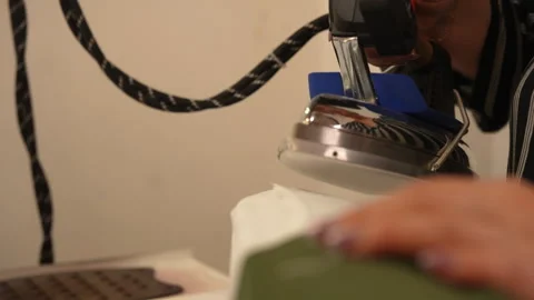 Close-up of unrecognizable female tailor using industrial iron to smooth out Stock Footage 310881872