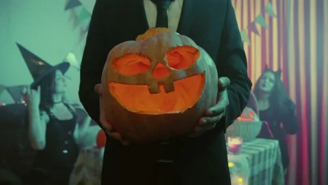 Close-up of an unrecognizable guy holding a Jack-o'-lantern for Halloween Video stock 211440021